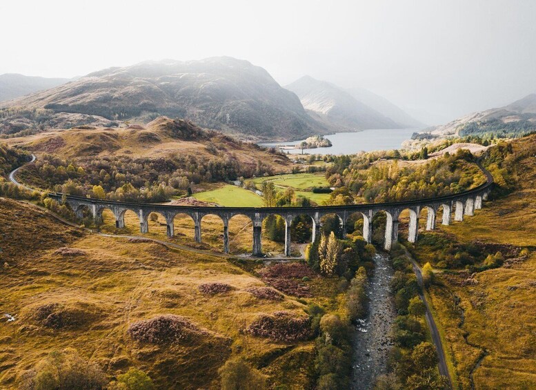 A bridge over a river in a hilly landscape with mountains in the background. 1