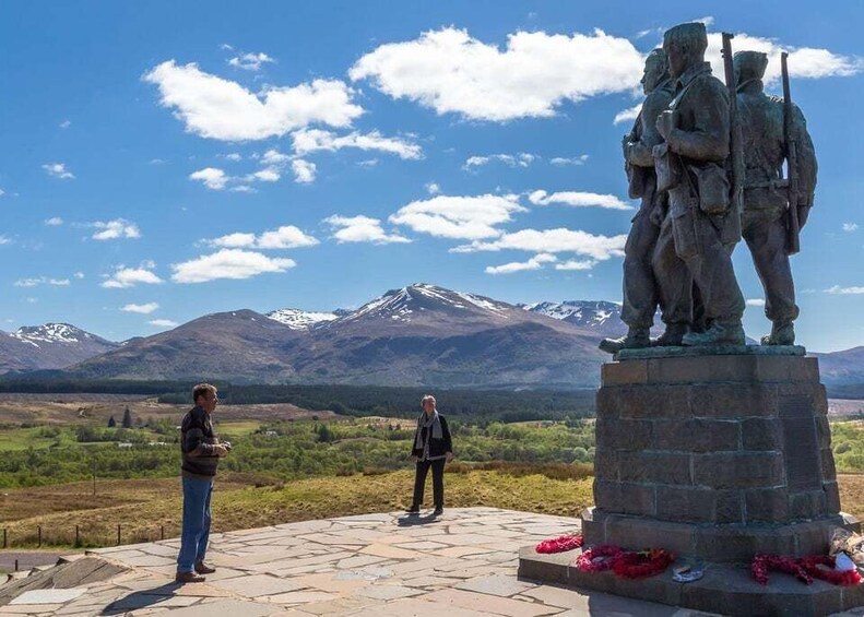 A statue of soldiers on a pedestal with a mountainous landscape in the background. 5