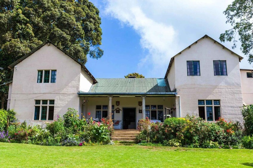 A two-story house with a green roof, surrounded by a well-maintained garden with various flowers and a lawn. 3