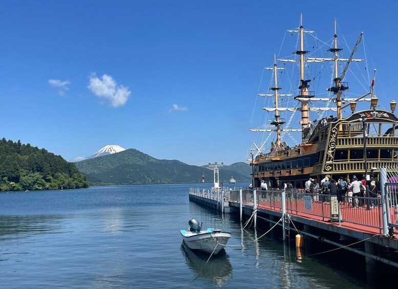 A traditional sailing ship docked at a pier with a mountainous backdrop. 1
