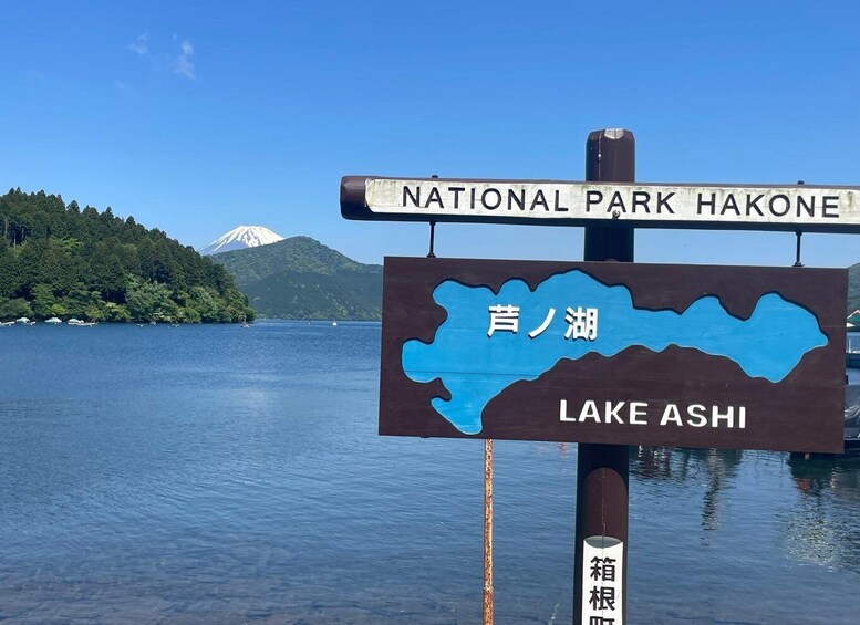 A sign for National Park Hakone and Lake Ashi with a mountain in the background. 2