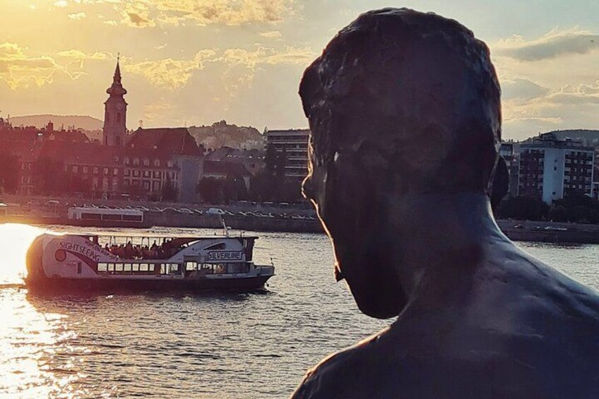 A statue of a man with a river and a boat in the background. 5