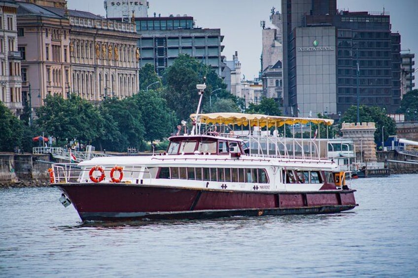A large boat with lifebuoys on the side, a yellow canopy, and a cityscape in the background. 4