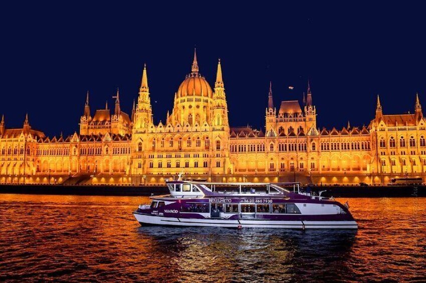 A boat in front of a brightly lit historic building at night. 4