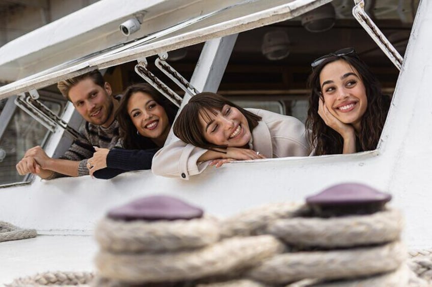 A group of people leaning out of a boat's open window, with a rope and a purple object in the foreground. 1