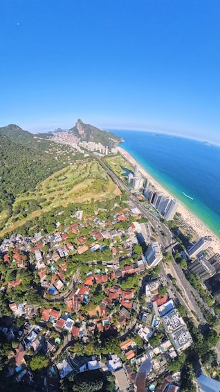 An aerial view of a coastal city with a prominent mountain, a beach, and dense residential areas. 3