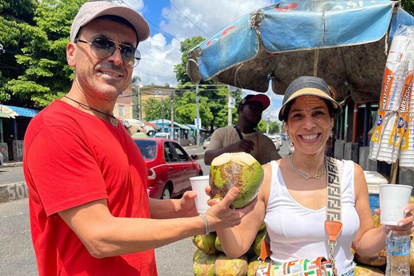 A street vendor selling coconuts and beverages, with a red car and a blue umbrella in the background. 3