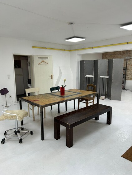 A conference room with a large table, chairs, a bench, a hanging coat rack, and a potted plant. 3