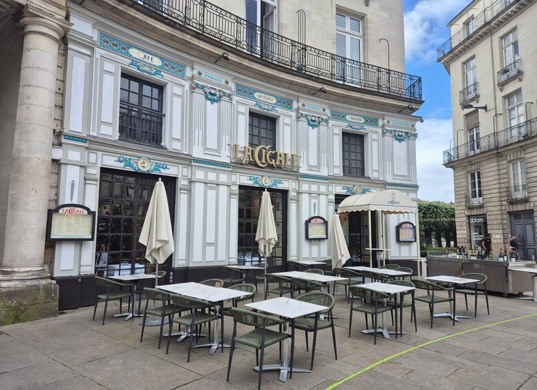 A cafe named 'LA CIGALE' with outdoor seating and a classic European architectural style. 2