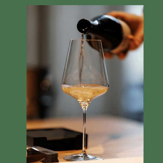 A person pouring a golden liquid into a clear glass. 1