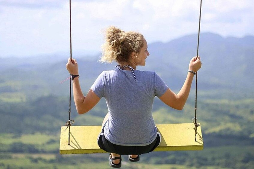 A person sitting on a swing with a mountainous landscape in the background. 5