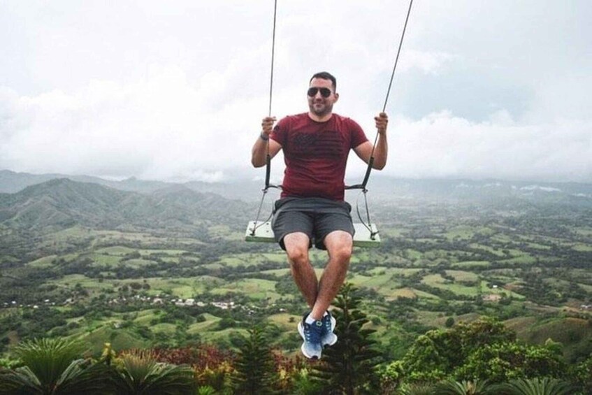 A person on a swing overlooking a mountainous landscape. 4