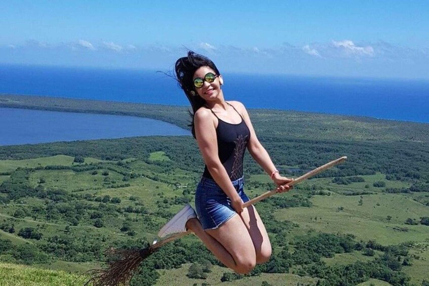A person flying with a broom over a green landscape and a body of water in the background. 2