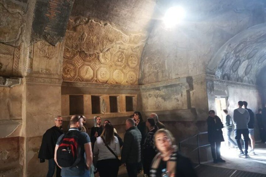 A group of people inside a historical building with detailed wall carvings and a high arched ceiling. 5
