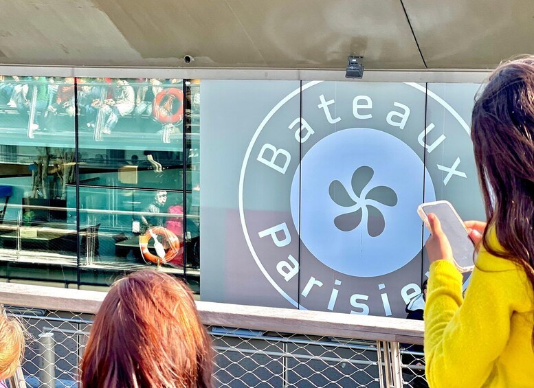 A storefront with a large sign reading 'Bateaux Paris' and a glass window reflecting people. 5
