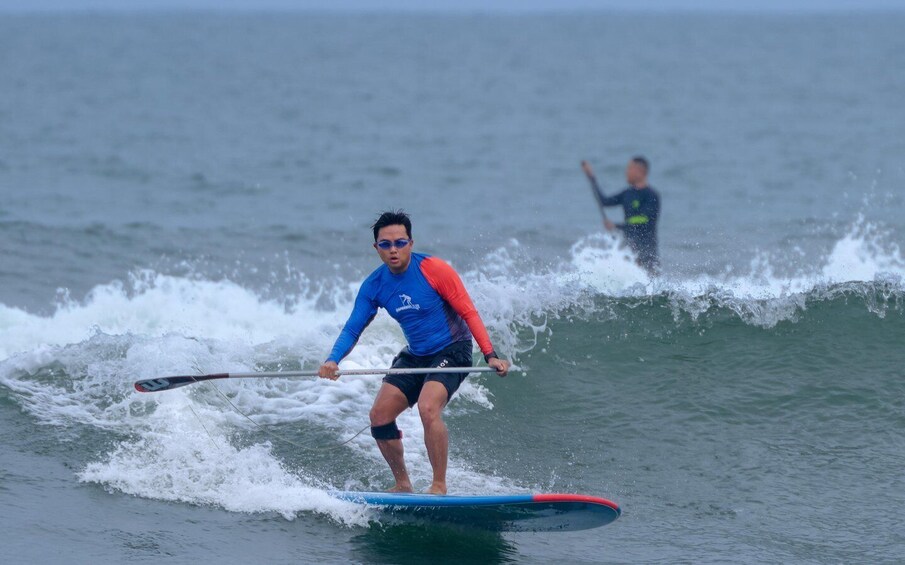 A person paddleboarding on a wave. 3