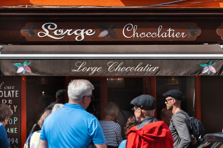 A storefront with the sign 'Lorge Chocolatier' and a group of people outside. 3