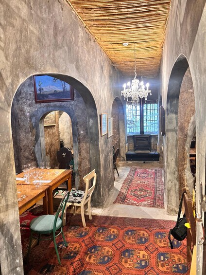 A rustic interior with a wooden table, chairs, a chandelier, and patterned rugs. 5