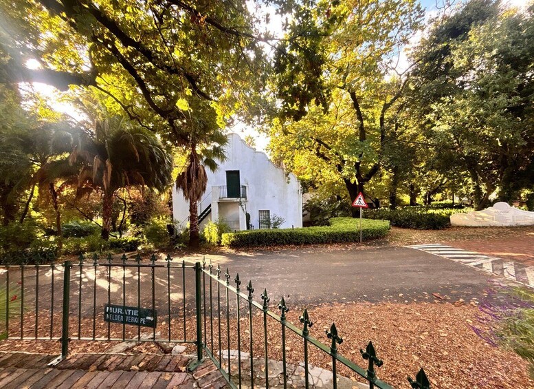 A white building with a green door, surrounded by trees and a pedestrian crossing sign. 3