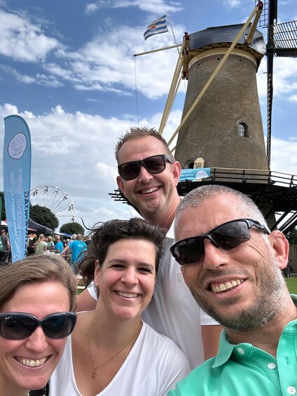 A group of people in front of a windmill and a Ferris wheel. 3