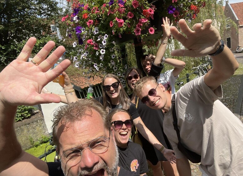 A group of people outdoors with a tree full of colorful flowers in the background. 4