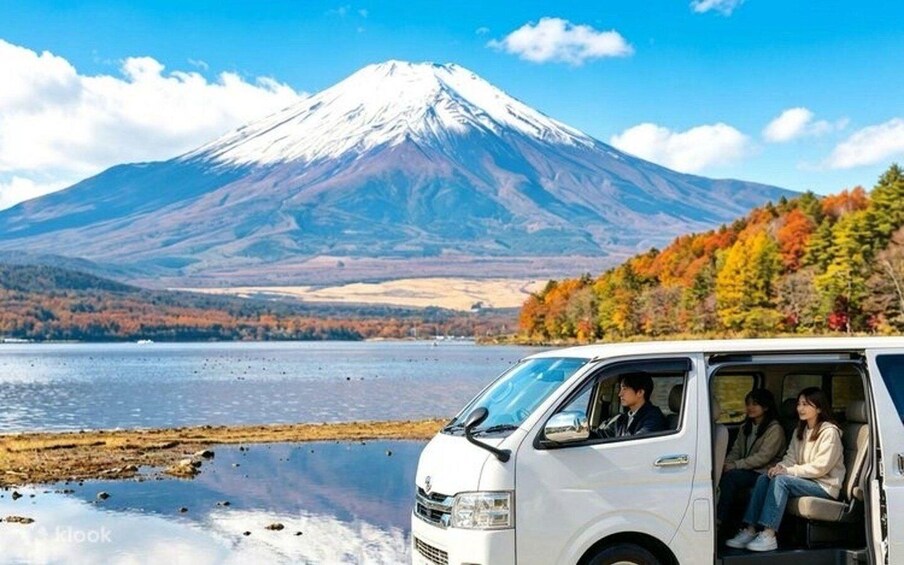 A white van parked by a lake with a snow-capped mountain in the background. 4