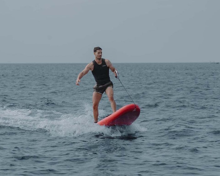 A person wakeboarding on a red board in the ocean. 4