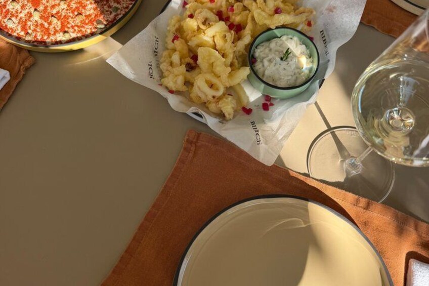 A table with a plate of food, a glass of wine, and a small bowl of sauce. 5