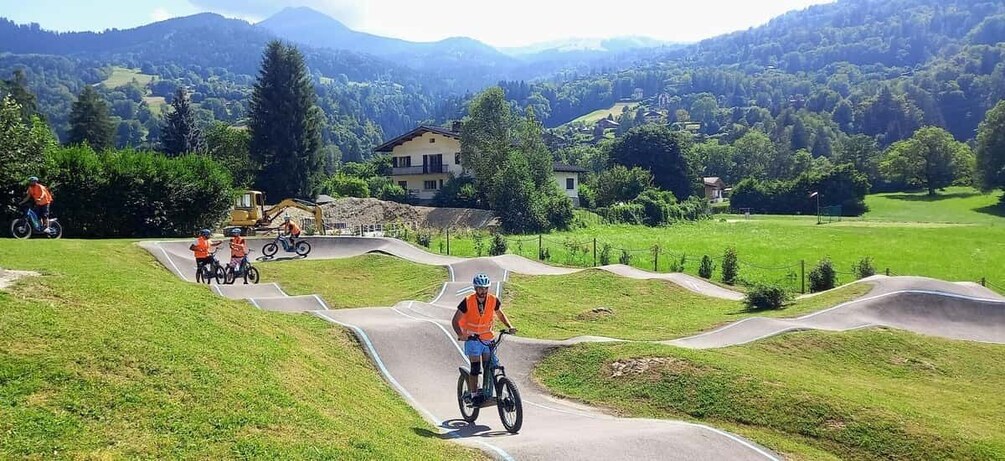 A mountain biking trail with riders, a clear sky, and a rural landscape with houses and trees. 3