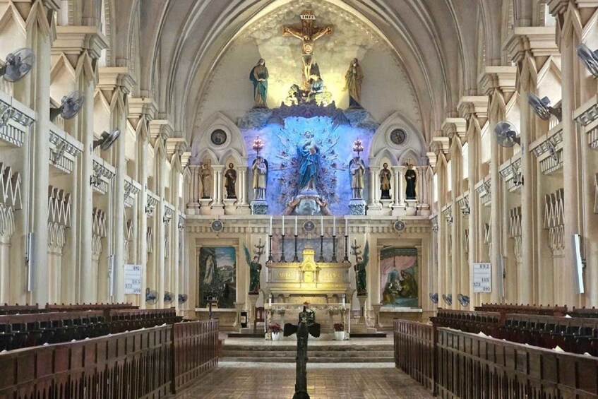 An interior of a church with a high arched ceiling, a central altar, and statues lining the walls. 3