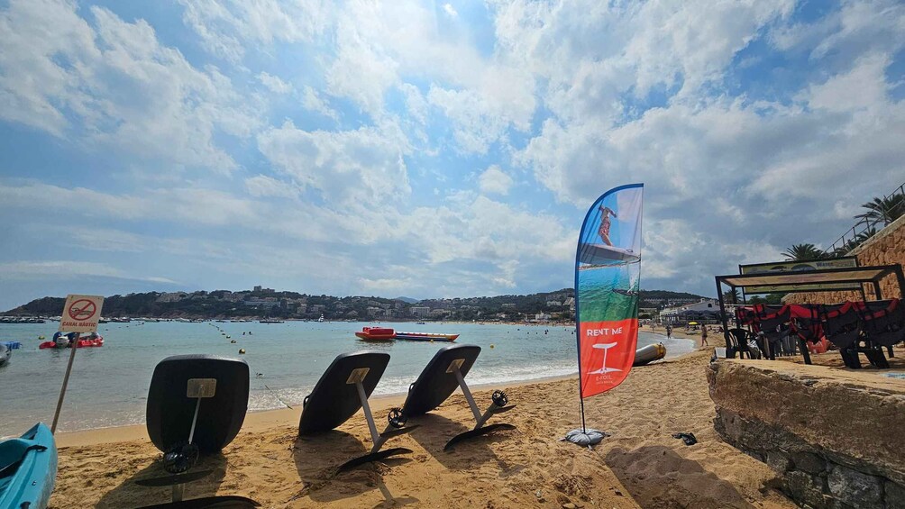A beach with surfboards, a sail, and a 'RENT ME' flag. 2