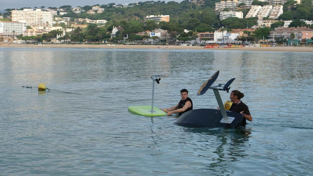 Two people on a water treadmill in a lake with a cityscape in the background. 4