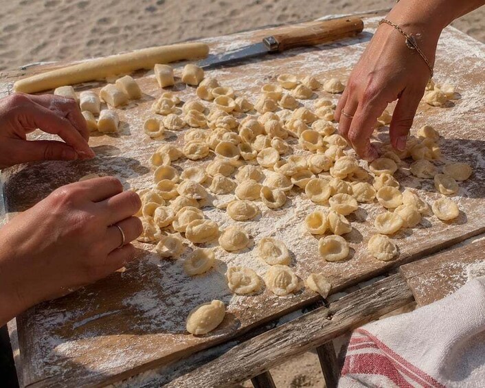 Hands shaping dough on a wooden surface with flour scattered around. 4