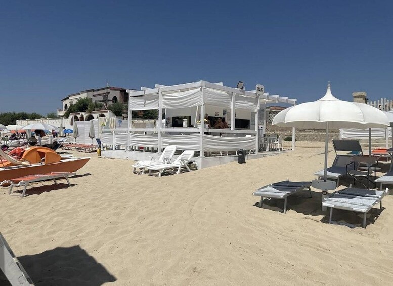 A beach with white canopies, lounge chairs, and a bar area. 3
