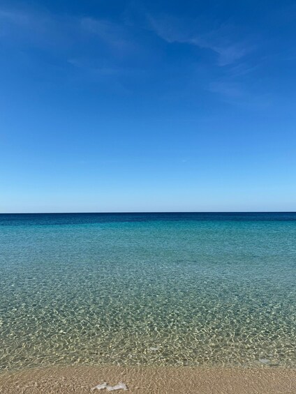 A clear blue sky, calm sea, and a sandy beach. 2