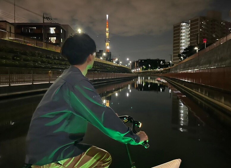 A person on a boat in a canal with a city skyline in the background. 4