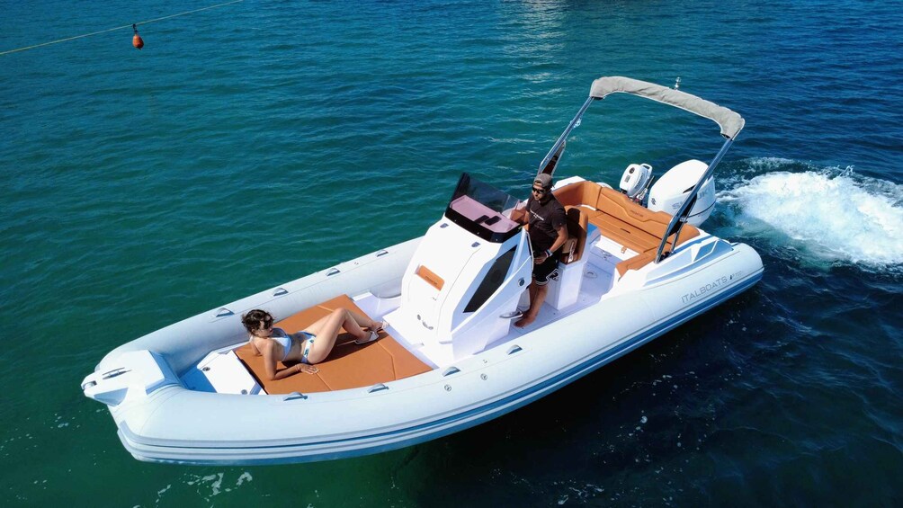 A white motorboat with a canopy, two people on board, and a wake behind it. 2