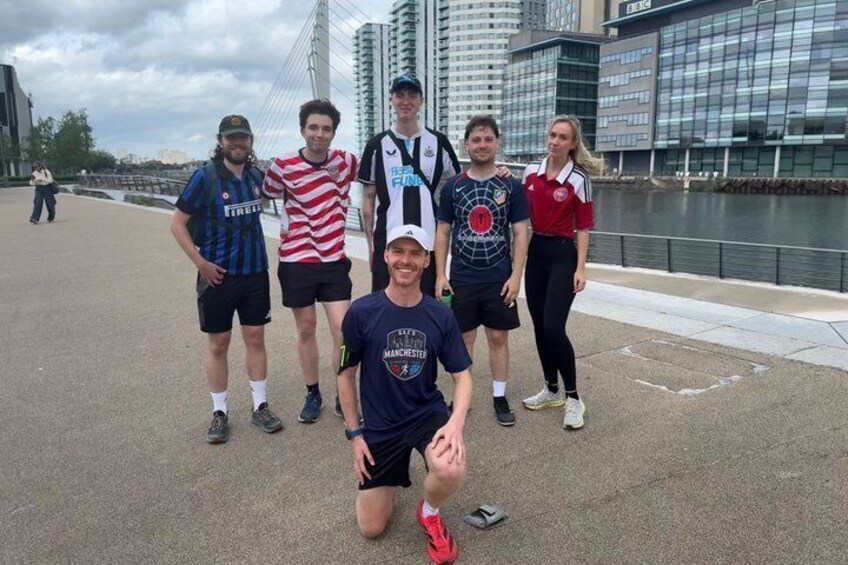 A group of people posing on a waterfront promenade with modern buildings in the background. 5