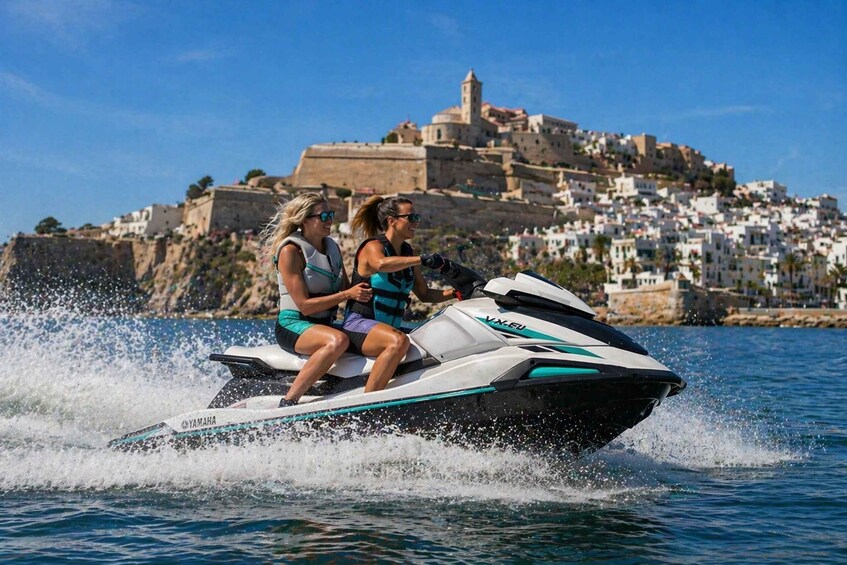 Two people jet-skiing on a body of water with a historic town and castle in the background. 1