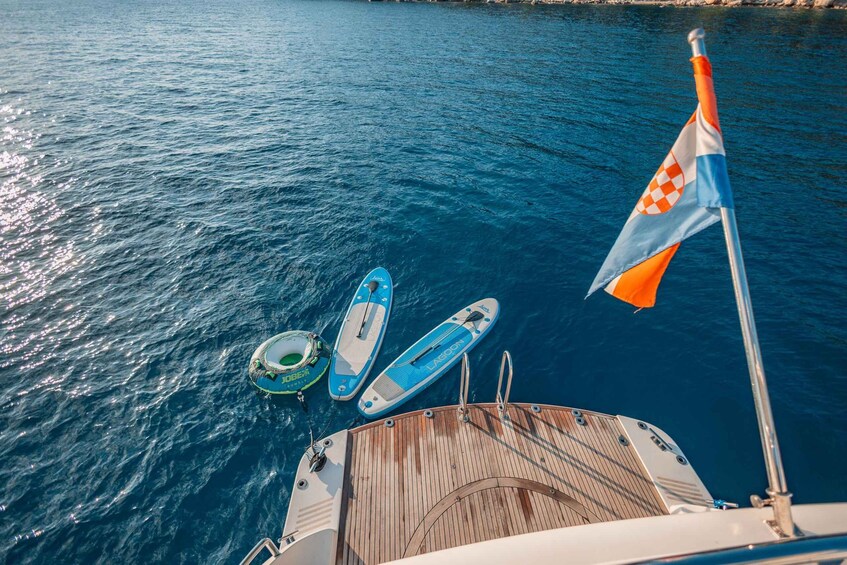 A boat with a flag, two blue paddleboards, and a green inflatable ring. 4