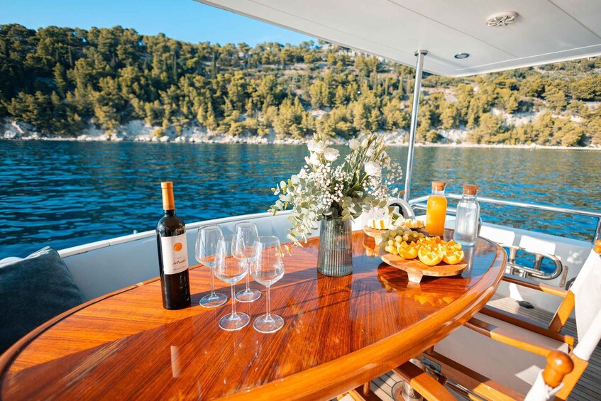A wooden table with a bottle of wine, glasses, a vase with flowers, and a fruit basket on a boat. 5