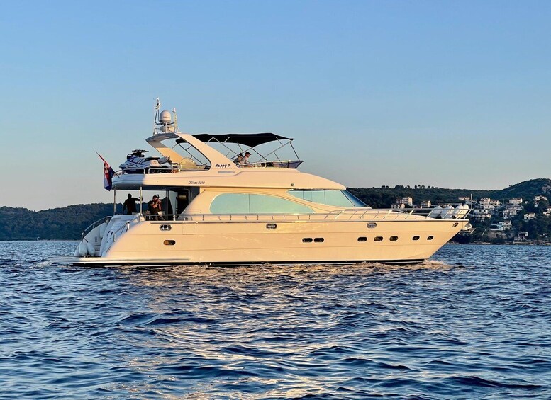 A large yacht named 'Happy 3' with a cabin and deck seating, sailing on a calm body of water with a coastal landscape in the background. 1