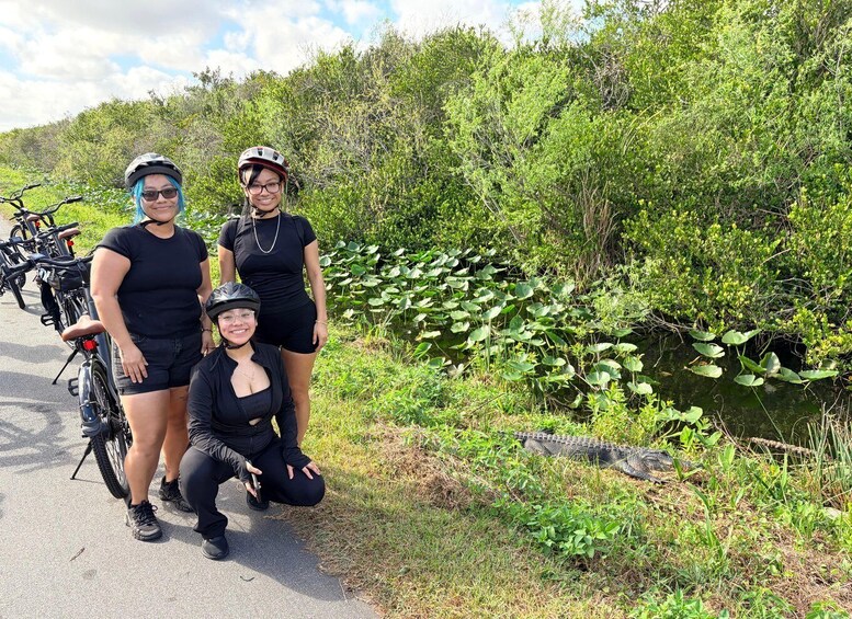 Three people with bicycles, a paved path, and dense greenery. 5