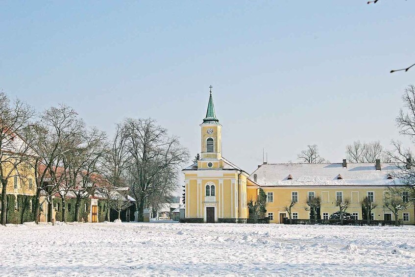 A church with a green spire and a clock tower, surrounded by snow-covered buildings. 2