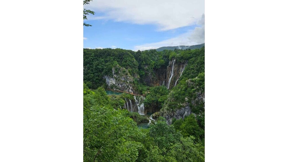 A lush green valley with multiple waterfalls cascading down cliffs. 3