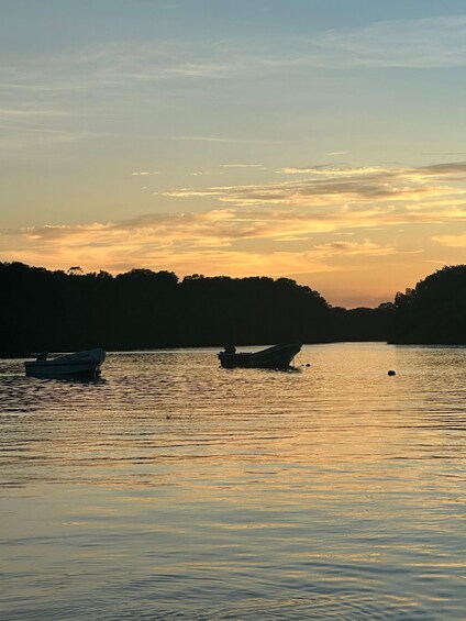 A calm lake at sunset with boats anchored. 5
