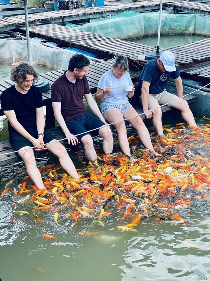 People sitting by a pond with colorful koi fish. 1