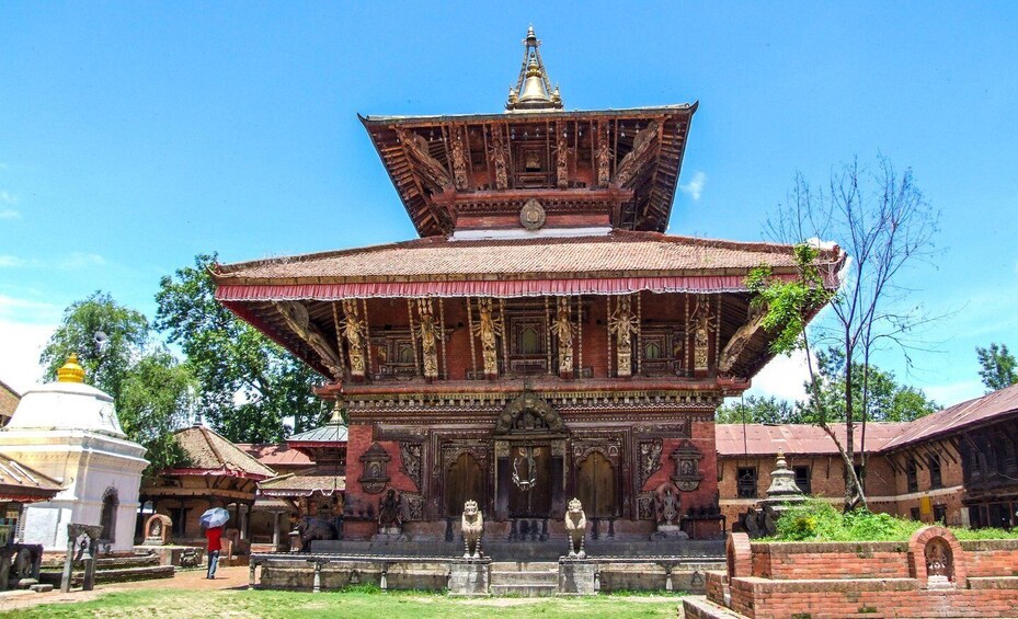 A traditional multi-tiered temple with intricate carvings and a bell on top. 2