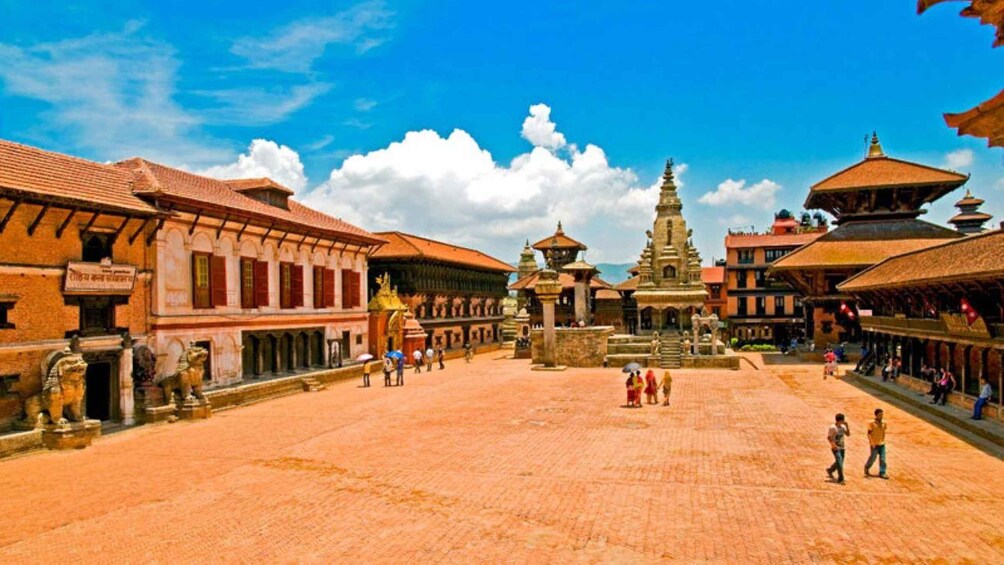 A traditional square with historic buildings, a central stupa, and people walking. 1