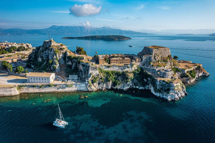 An aerial view of a coastal town with historic fortifications, clear blue waters, and a sailboat. 2